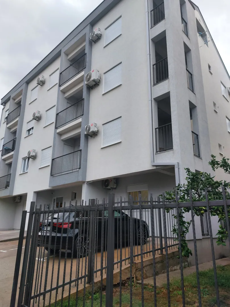Exterior view of a modern residential building with balconies and parking.