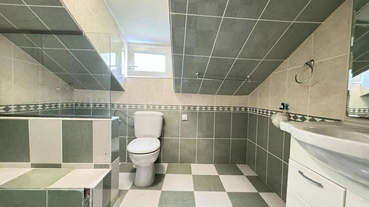 Kupatilo u potkrovlju sa tuš kabinom, toaletom i umivaonikom.