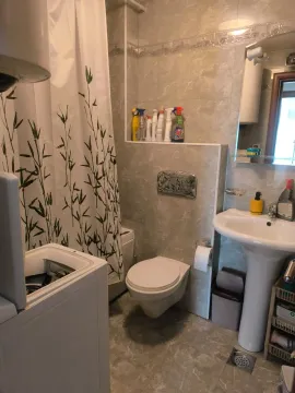 Bathroom with a washbasin, toilet, shower, and washing machine. - image 6