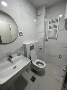 Modern bathroom with bright marble tiles and a round mirror. - image 4