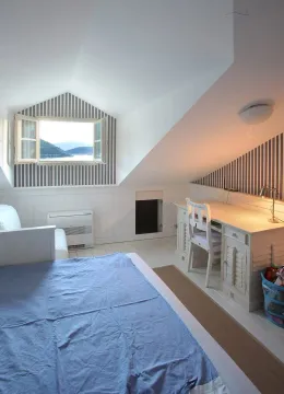 Attic bedroom furnished with a bed and desk, featuring a sea view. - image 8
