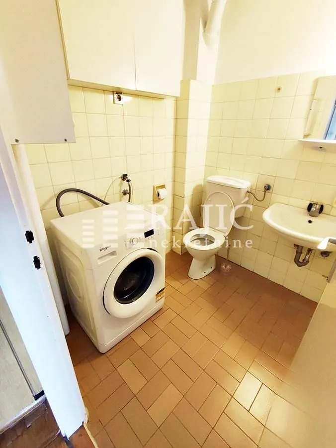 Smaller bathroom with sanitary facilities and a washing machine.