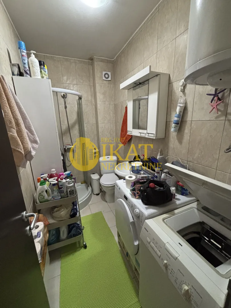 Kupatilo opremljeno tuš kabinom, sanitarijama i mašinama za pranje veša.