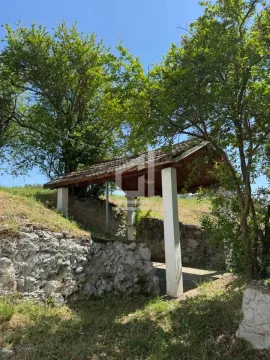 Covered porch with stone walls surrounded by greenery. - image 2