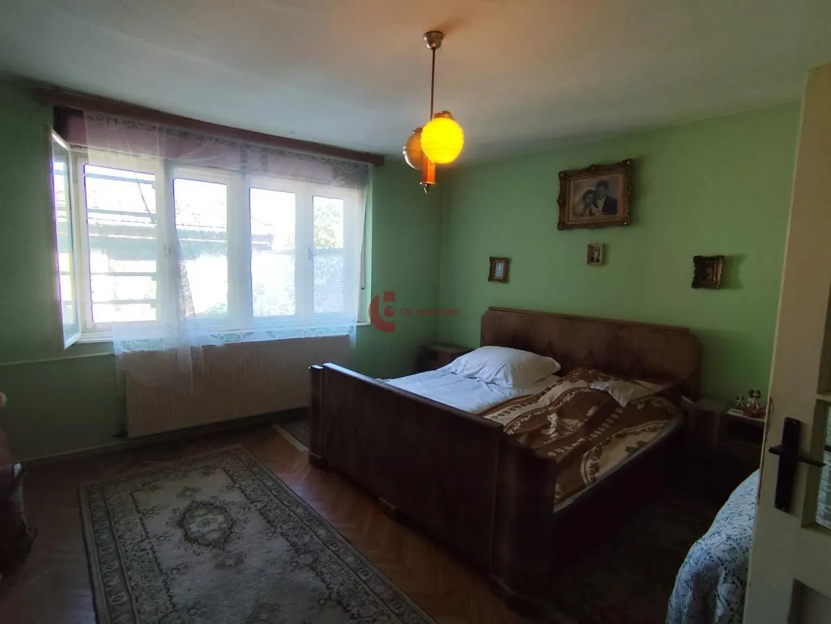 Spavaća soba sa bračnim krevetom, zelenim zidovima i prozorom.