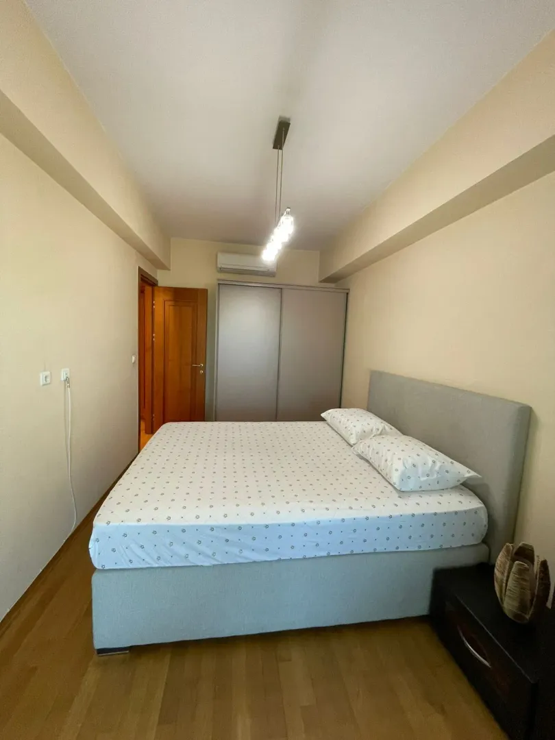 Namještena spavaća soba sa bračnim krevetom i garderoberom.