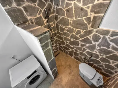 Kupatilo sa tuš kabinom obloženom kamenom i veš mašinom. - image 10