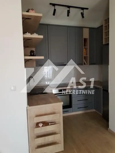 Moderna kuhinja sa sivim elementima i drvenim detaljima.