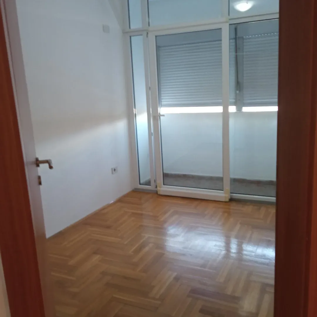 Empty room with parquet flooring and balcony door.