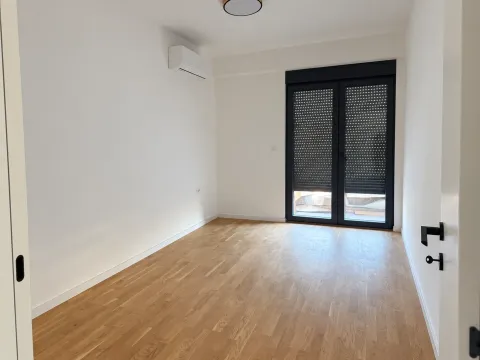 Prazna soba sa parketom, klima uređajem i balkonskim vratima sa roletnama. - image 8
