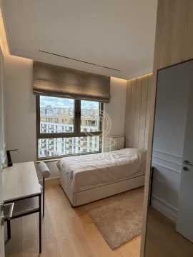 Small bedroom with a bed, desk, and a window with a city view. - image 10