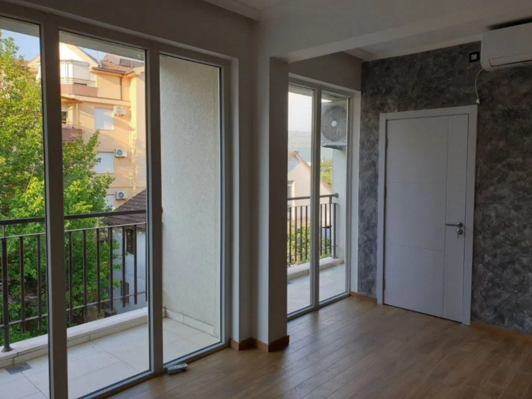 Bright empty room with large glass doors leading to balconies.