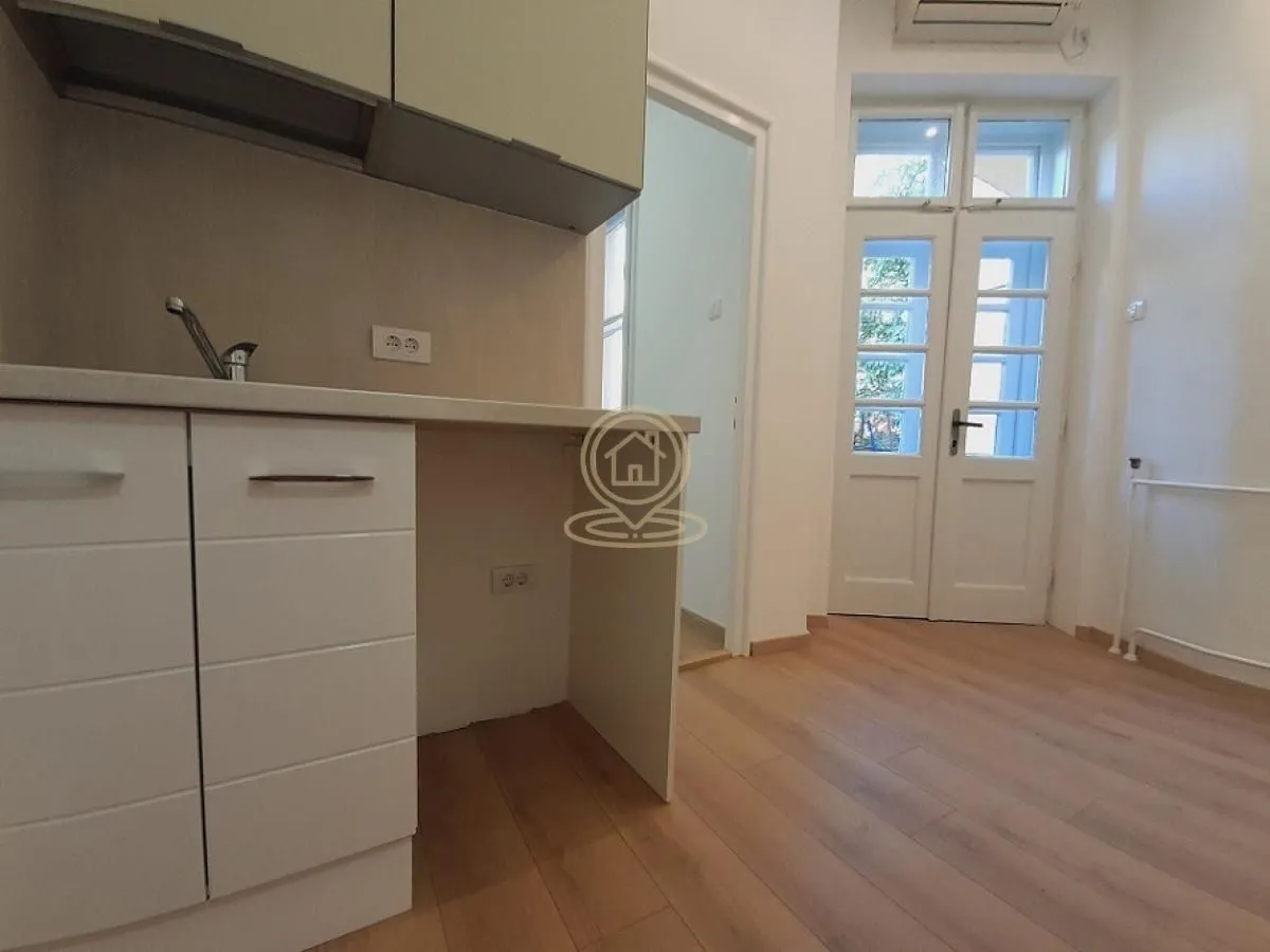 Smaller kitchen with white cabinetry and wooden flooring.