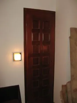 Wooden interior door with decorative panels and a lit wall lamp. - image 11
