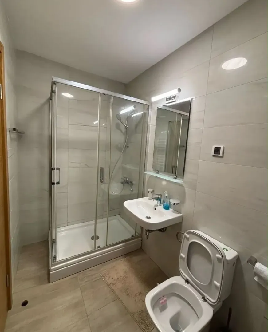 Moderne kupatilo sa tuš kabinom, umivaonikom i toaletom.
