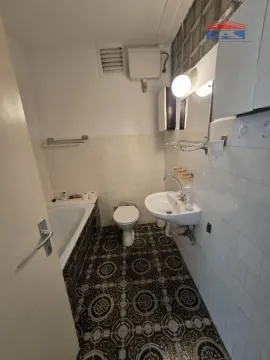 Smaller bathroom with a bathtub, washbasin, and toilet. - image 11