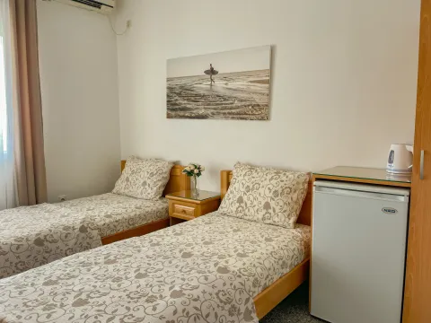 Bedroom with two single beds and a small refrigerator. - image 3