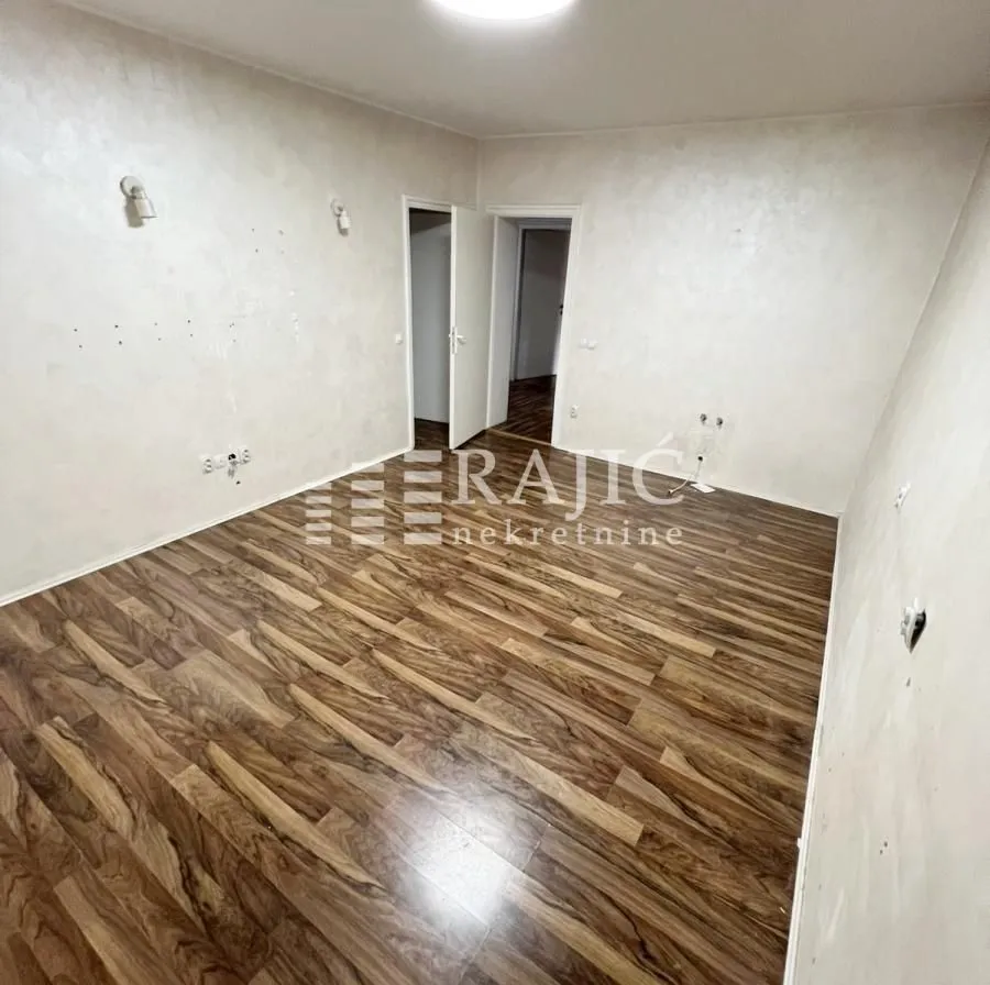 Empty room with laminate flooring and light-colored walls.