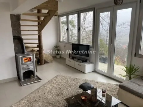 Living room with a wood-burning stove, stairs, and large windows overlooking nature. - image 18