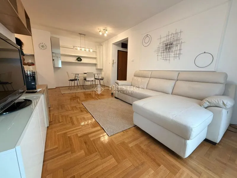 Living room with sofa and dining area in the background.