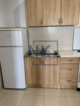Compact kitchen with wooden cabinets, refrigerator, and sink. - image 4