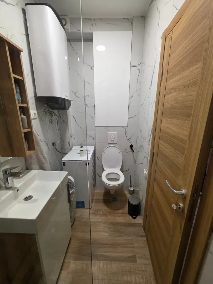 Moderne kupatilo sa umivaonikom, WC šoljom, bojlerom i veš mašinom.