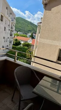 Namješten balkon sa stolom i stolicama i pogledom na okolne zgrade i brdo. - image 5