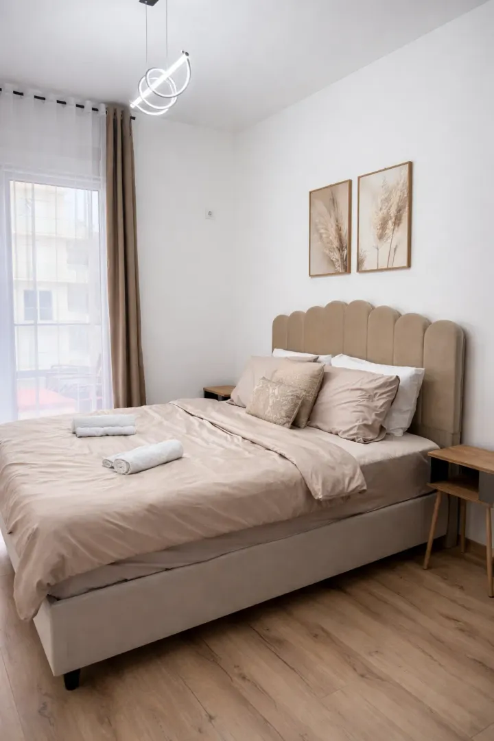 Furnished bedroom with a double bed, wooden flooring, and balcony doors.