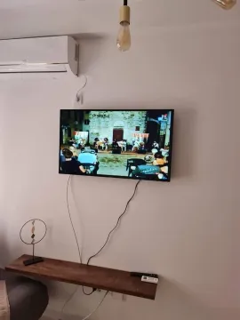 Televizor na zidu u dnevnoj sobi sa klima-uređajem iznad. - image 9