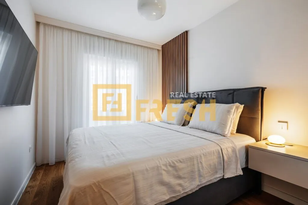 Modern bedroom with a double bed, white curtains, and wall panels.