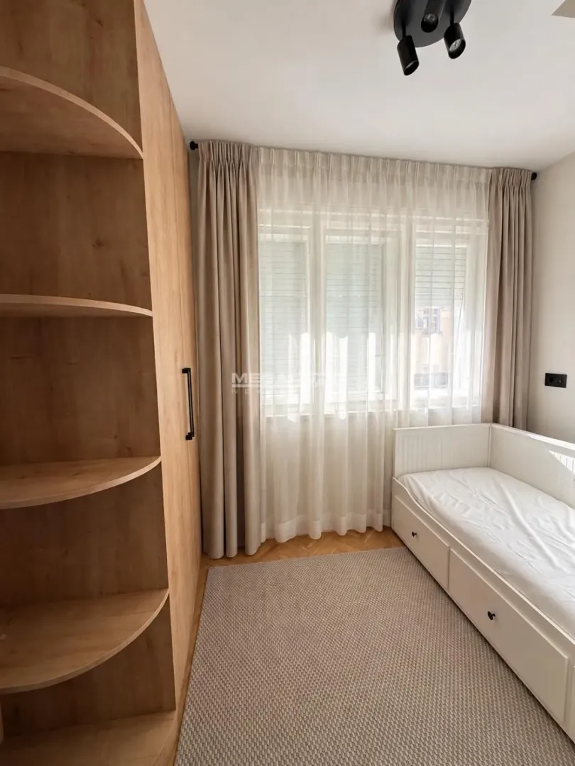 Children's bedroom with a bed, wardrobe, and a large window with curtains.