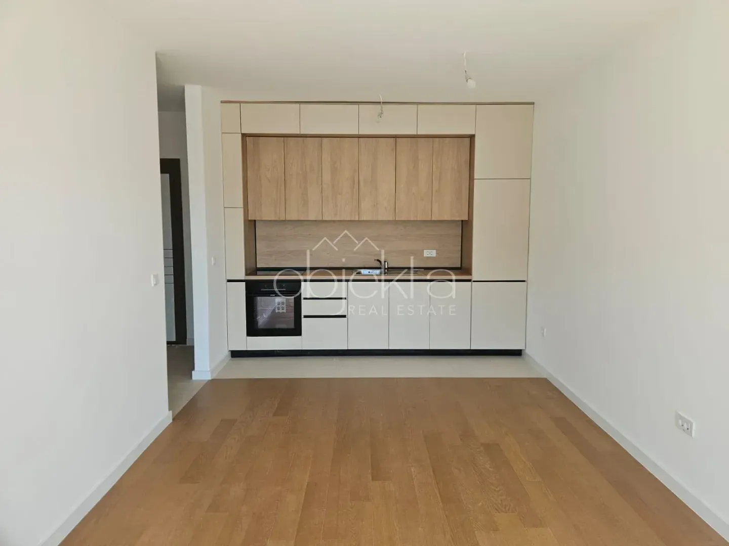 Moderna kuhinja sa drvenim elementima i ugradnim uređajima u praznom prostoru.