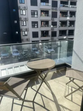 Furnished balcony with a table and two chairs and a view of the building. - image 10