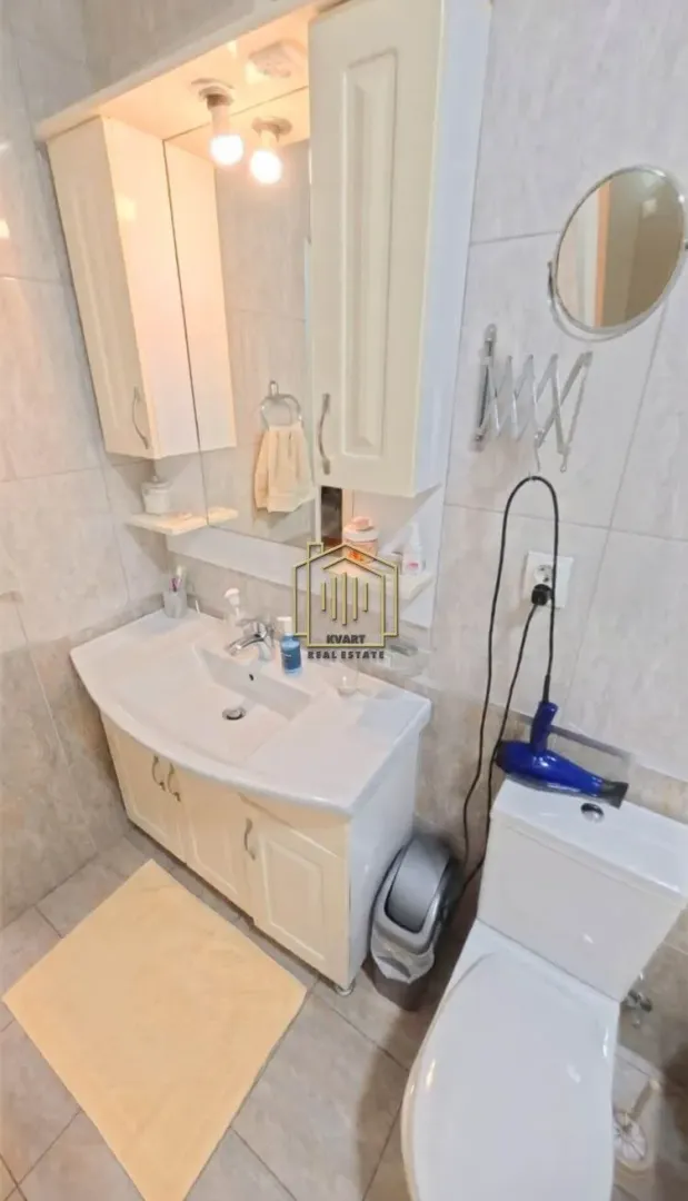 Bathroom with a sink, mirror, cabinet, and toilet.