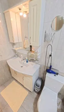 Bathroom with a sink, mirror, cabinet, and toilet. - image 10