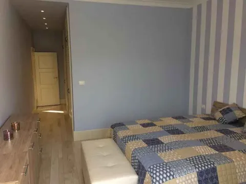 Svijetla spavaća soba sa bračnim krevetom i prugastim zidom. - image 7