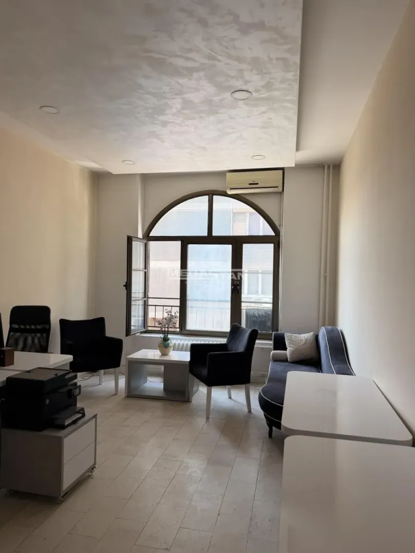 Living room with seating furniture, a table, and a large arched window.