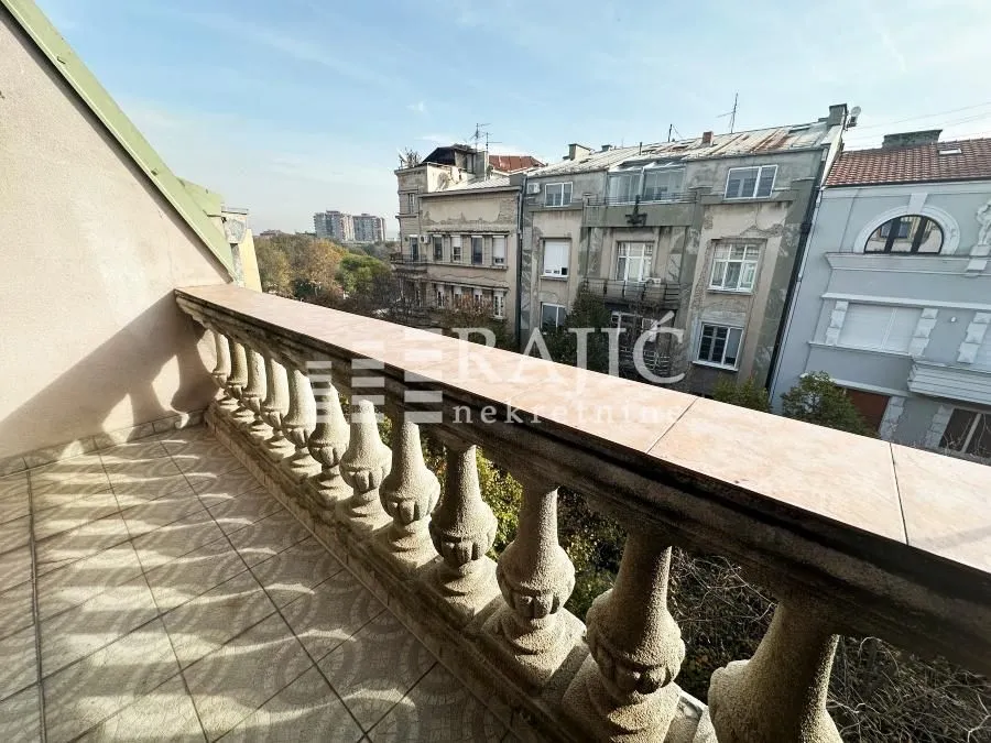 Balcony with a stone railing and city view.