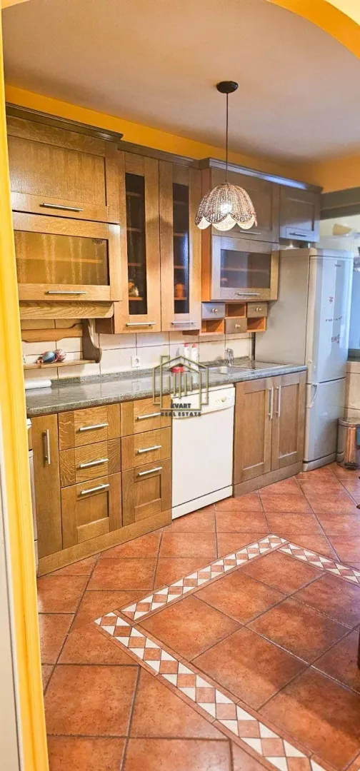 Kuhinja sa drvenim elementima i keramičkim pločicama na podu.