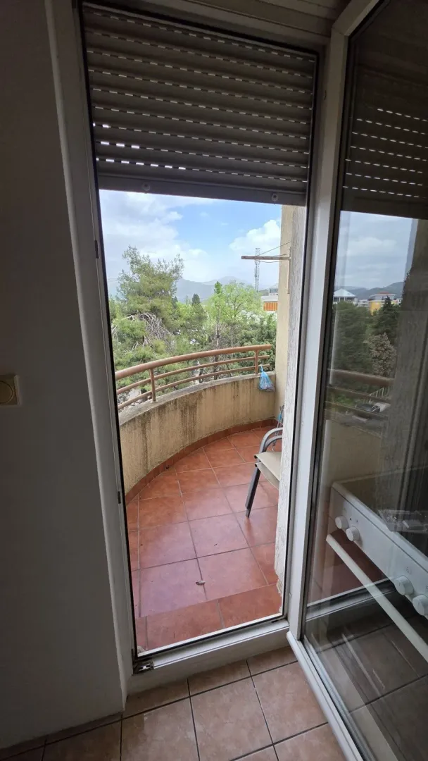 View of a semi-circular tiled balcony through an open door.