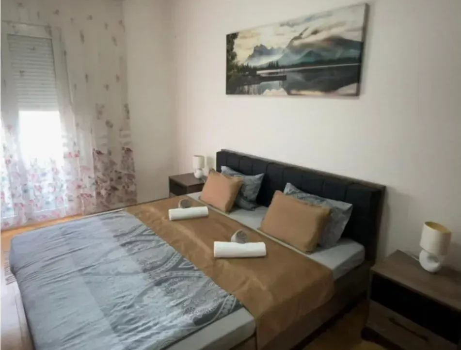 Namještena spavaća soba sa bračnim krevetom i noćnim stočićima.