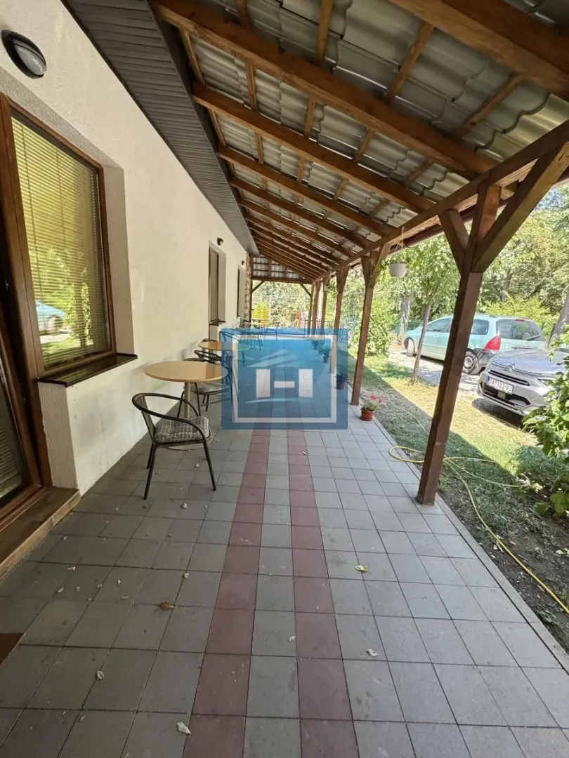 Covered terrace with tables and chairs in front of the house.