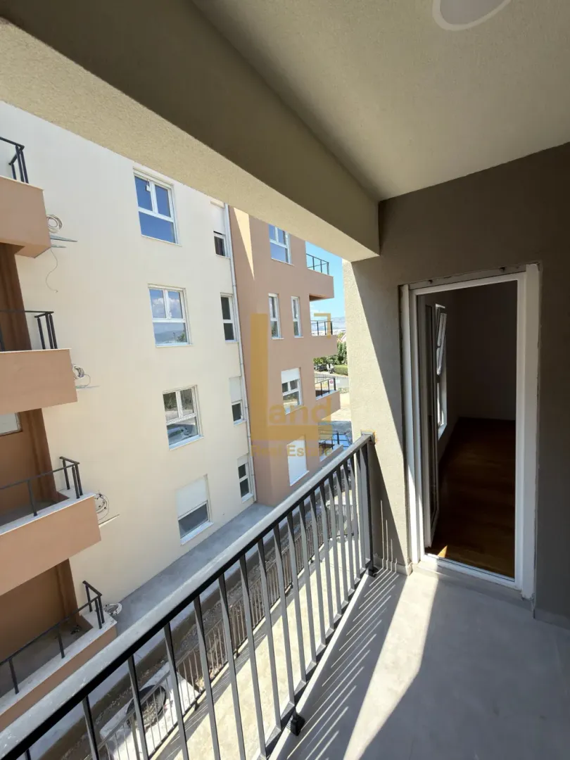 Nenamješten balkon sa pogledom na susjednu zgradu.