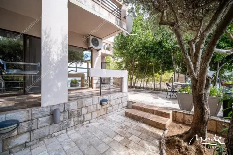 Pogled na popločano dvorište i terasu kuće okružene zelenilom. - image 17