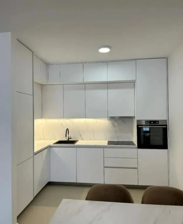 Modern white kitchen with built-in appliances and a sink.
