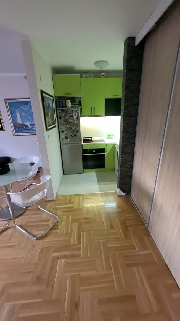 Manja kuhinja sa zelenim elementima i ugradnim aparatima u produžetku trpezarije.