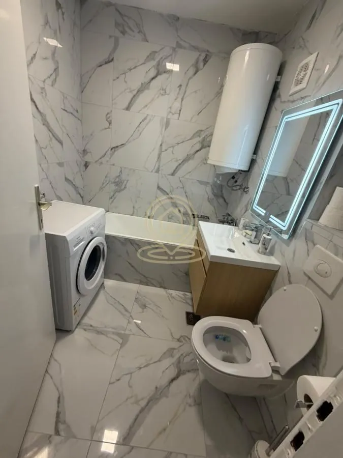 Moderno opremljeno kupatilo sa kadom, umivaonikom, wc šoljom i veš mašinom.
