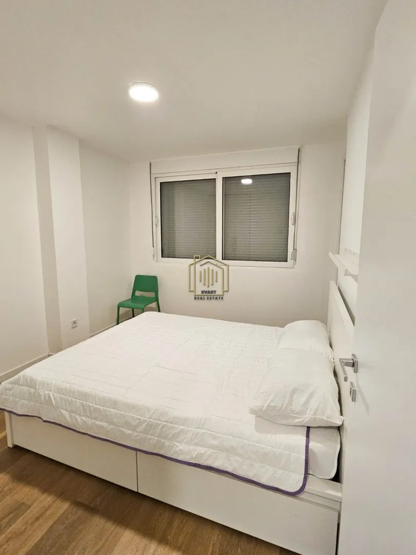 Svijetla spavaća soba sa bračnim krevetom i prozorom.