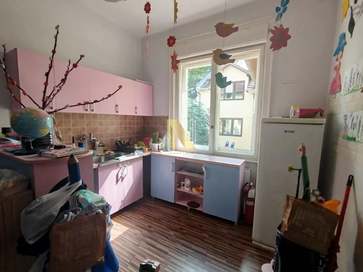 Small kitchen in pink and blue tones with cabinets and a refrigerator.