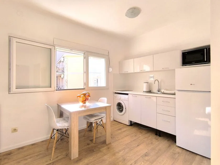 Small bright kitchen with a dining table and white cabinetry.